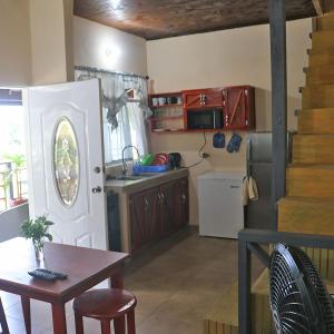 a kitchen with a table and a kitchen with a table and a door at La Casa de Castara in Castara
