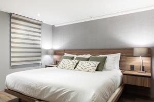 a bedroom with a large white bed with a wooden headboard at Capitalia - Apartments - Polanco - Julio Verne in Mexico City