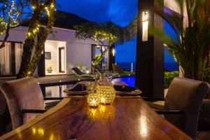 a wooden table with chairs and glasses on a patio at Nusa Dua Ocean Cliff Dream in Ungasan