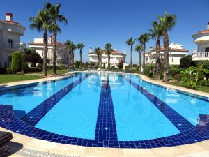 a large swimming pool with palm trees and buildings at TALYA TURİZM TATİLEVLERİ ve VİLLALARI in Belek