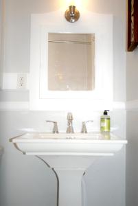 lavabo blanco en el baño con espejo en Black and white cottage; Simple yet stunning., en Joplin