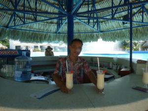 un hombre sentado en una mesa con dos tragos en Costa Azul Suites 403 en Santa Marta