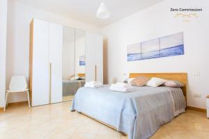 a white bedroom with a bed and a chair at Casa Vacanze Licinia - Appartamento centro storico in Citta' Sant'Angelo