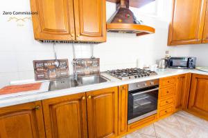 a kitchen with wooden cabinets and a sink and a stove at Casa Vacanze Licinia - Appartamento centro storico in Citta' Sant'Angelo