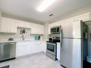 a kitchen with white cabinets and a stainless steel refrigerator at Forever Summer - Entire House! with KING Bed! in Clearwater