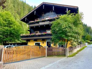 a black and yellow house with flowers on the windows at Pension Lederergütl - Jokercard & Parkplatz inkl in Saalbach Hinterglemm