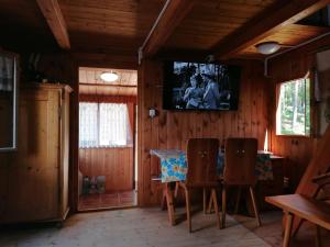 a dining room with a table and a tv on the wall at Chata Florián in Stráž