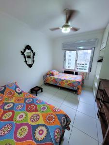 a bedroom with two beds and a ceiling fan at Apto pé na areia Praia das Pitangueiras - Centro in Guarujá