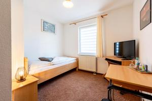 Dormitorio con cama, escritorio y TV en Pension & Gaststätte Zur Salzgrube, en Sondershausen