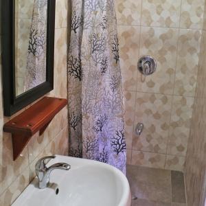 a bathroom with a sink and a shower curtain at La Casa de Castara in Castara