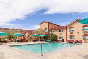 a pool at a hotel with chairs and umbrellas at Aarchway Inn in Moab
