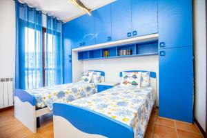 una camera blu con due letti e armadi blu di L ARGENTIERA appartamento con posto auto a Porto Santo Stefano