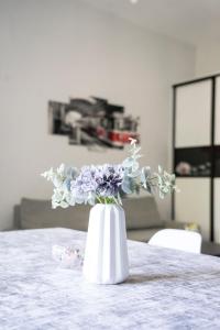eine weiße Vase mit lila Blumen auf einem Tisch in der Unterkunft Apartament "Przy Dworcu" in Chojnice