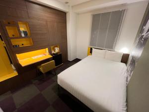 a hotel room with a white bed and a desk at Henn na Hotel Tokyo Haneda in Tokyo