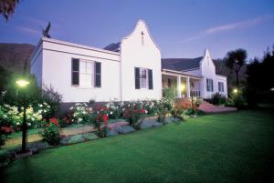 a white house with flowers in a yard at Altes Landhaus Country Lodge in Oudtshoorn