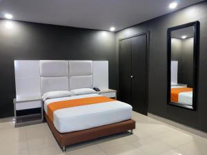 a bedroom with a large white bed and a mirror at Hotel Latino Medellín in Medellín