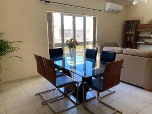 uma sala de jantar com uma mesa de vidro e cadeiras em Newly Refurbished Mellieha Central apartment em Mellieħa