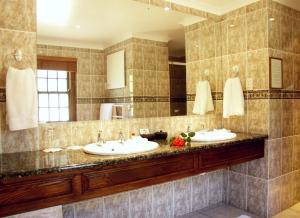 a bathroom with two sinks and a large mirror at Altes Landhaus Country Lodge in Oudtshoorn