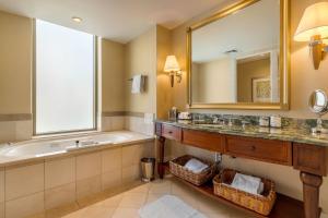 a bathroom with two sinks, a mirror and a bath tub at Mokara Hotel & Spa in San Antonio