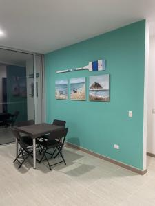 a table and chairs in a room with a blue wall at Espectacular Apartamento Sierra Beach Resort in Santa Marta