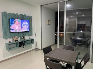 sala de estar con mesa y TV en la pared en Espectacular Apartamento Sierra Beach Resort en Santa Marta