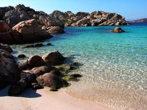 a beach with rocks and blue water and sand at PORTO POLLO WIND & LOVE in Barrabisa +3 photos