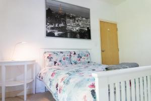 a bedroom with a white bed with a floral bedspread at Elphinstone HomeShare in Portsmouth