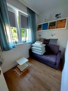 ein Wohnzimmer mit einem lila Sofa und 2 Fenstern in der Unterkunft Apartament Prima in Lubniewice
