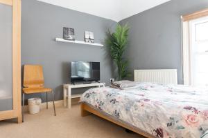 a bedroom with a bed and a tv and a chair at Elphinstone HomeShare in Portsmouth