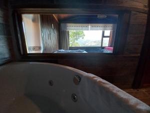 a bath tub in a bathroom with a large mirror at Gödence Hotel Restoran Bungalow in Gödence