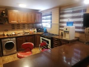 a kitchen with wooden cabinets and red chairs in it at Mhna guest house بيت الضيافة الريفي in Ajloun