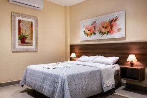 a hotel room with a bed and flowers on the wall at Hotel Fazenda Ararita in Pôrto Feliz