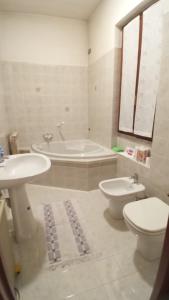 y baño con bañera, aseo y lavamanos. en Appartamento Kiwy, en Arsago Seprio