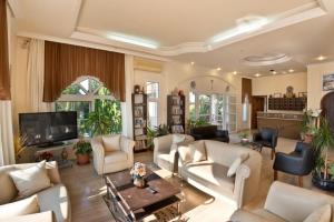 a living room with white furniture and a tv at Bare Hill Holiday Apartments in Kérynia