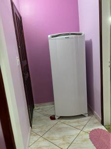 Una pequeña nevera en una habitación con paredes púrpuras. en Cantinho da tia Lira, en Cabo Frío