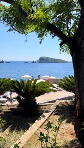 a beach with umbrellas and people swimming in the water at Villa Bojana in Utjeha