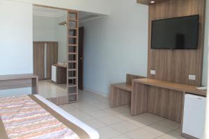 um quarto com uma televisão na parede e uma cama em Mato Grosso Palace Hotel em Cuiabá