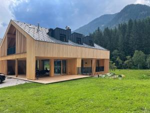 a house with a roof on top of a field at Villa Anita Chalets in Valle Di Casies