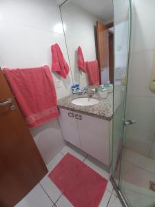 uma casa de banho com um lavatório e um chuveiro com toalhas vermelhas em Apartamento Barra Sky Vista Mar em Salvador