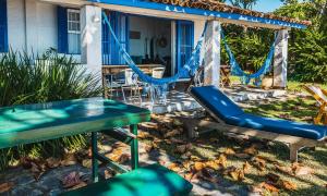 a patio with swings and a table and chairs at Casa pé na areia na Praia da Armação em Ilhabela in Ilhabela