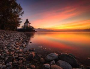 a lighthouse on the shore of a lake at sunset at Max in Liptovský Mikuláš