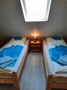 twee bedden in een kleine kamer met een raam bij Modernisierte Ferienwohnung Friedrichskoog - Spitze, gegenüber Mutter-Kind-Klinik in Friedrichskoog