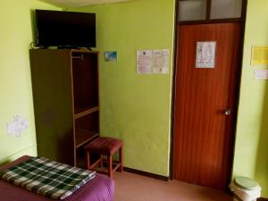 Habitación con cama, TV y puerta. en La Casa del Manzano, en Puno
