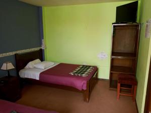 een kleine slaapkamer met een bed en een televisie bij La Casa del Manzano in Puno