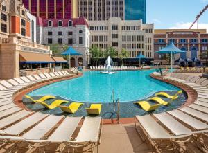 a large swimming pool with lounge chairs and buildings at New York-New York in Las Vegas