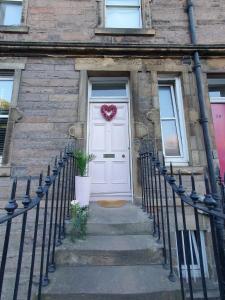 Eine weiße Tür mit einem Herzkranz drauf. in der Unterkunft The Flat with the Pink Door in Edinburgh