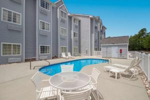 a patio with a table and chairs next to a pool at SureStay Hotel by Best Western Shallotte in Shallotte