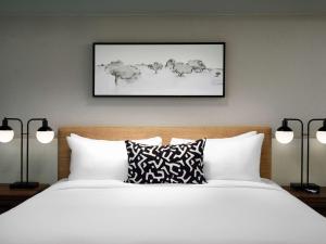 a bedroom with a bed with white sheets and two lamps at Sonesta Irvine in Irvine