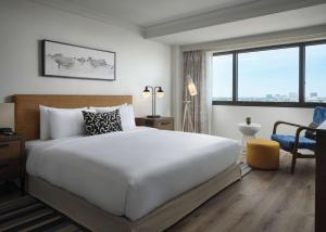 a bedroom with a large white bed and a desk at Sonesta Irvine John Wayne Airport in Irvine
