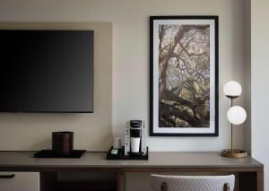 a desk with a coffee maker and a tv on a wall at Sonesta Irvine John Wayne Airport in Irvine +35 photos